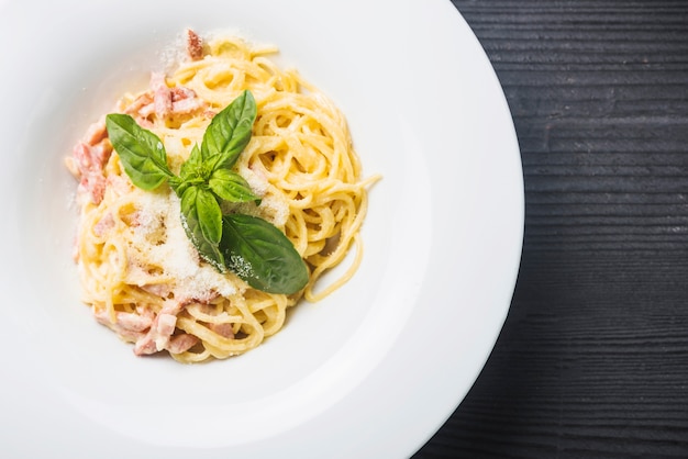 Una vista dall&#39;alto di spaghetti con foglie di basilico e formaggio