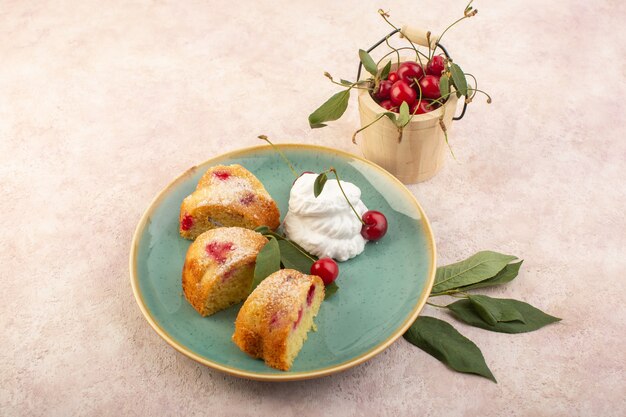 Una vista dall'alto fette di torta di ciliegie con crema all'interno del piatto rotondo sullo zucchero rosa biscotto torta da scrivania dolce