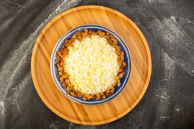 Una vista dall'alto gustoso pilaf con olio e uvetta essiccata all'interno del piatto sulla superficie scura
