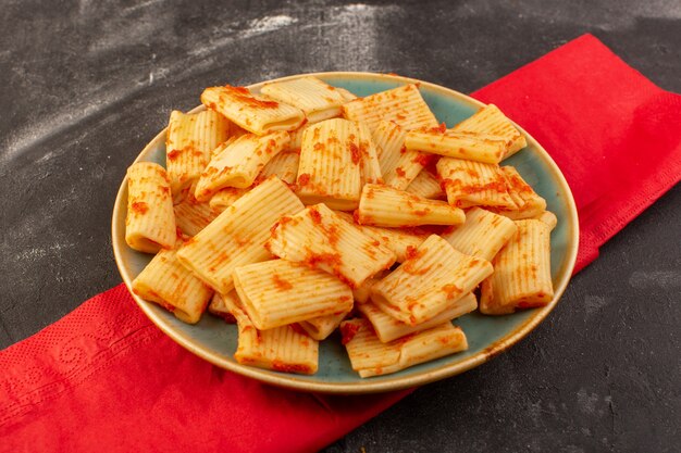 Una vista dall'alto ha cucinato la pasta italiana con salsa di pomodoro all'interno del piatto sulla pasta italiana del pasto dell'alimento della tavola scura