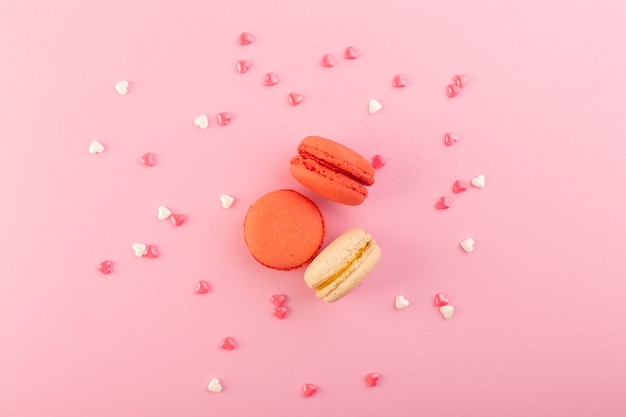 Una vista dall'alto macarons francesi rotondi e squisiti sullo zucchero rosa del biscotto della torta della tavola dolce