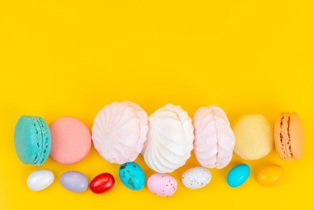 Una vista dall'alto meringhe e macarons deliziosi e dolci su caramelle arcobaleno di colore giallo