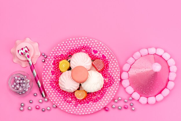 Una vista dall'alto meringhe e marmellate colorate insieme a fischietto di compleanno e collana in rosa, torta di zucchero dolce