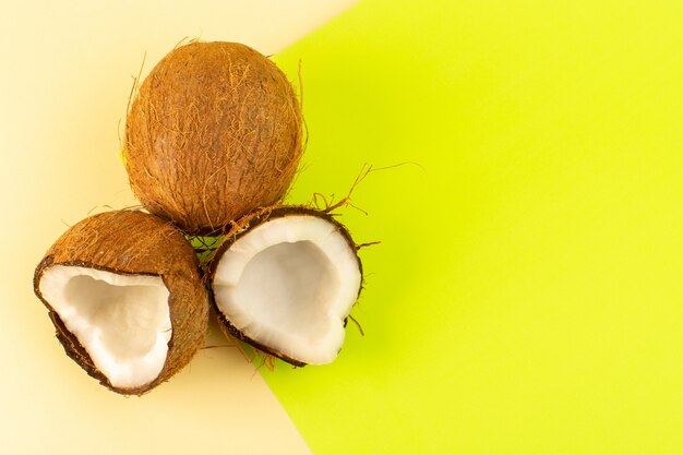 Una vista dall'alto noci di cocco intere e affettate latteo fresco dolce isolato sul color crema-pistacchio