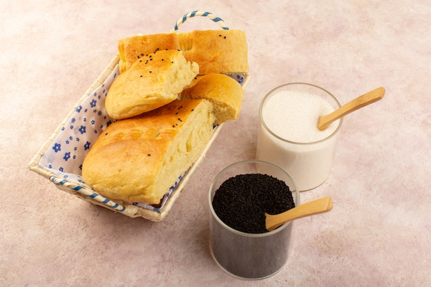 Una vista dall'alto pane cotto caldo gustoso affettato fresco all'interno del cestino del pane con sale e pepe sul rosa