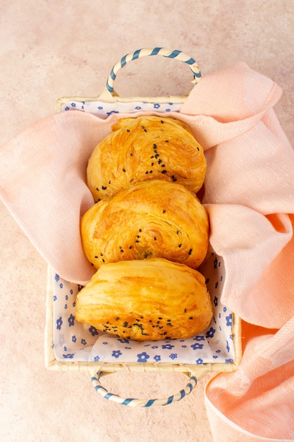 Una vista dall'alto panini al forno caldi gustosi freschi all'interno del cestino del pane sul rosa