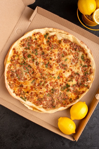 Una vista dall'alto pasta lahmacun con carne macinata insieme a verdure e limone all'interno della scatola di carta gustoso pasto di pasticceria