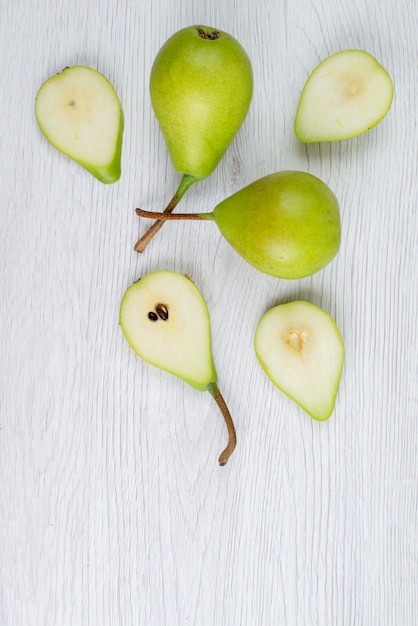 Una vista dall'alto pere verdi fresche affettate e intere sul colore della frutta bianca scrivania