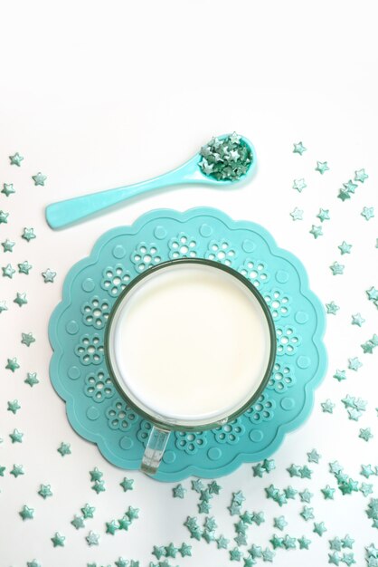 Una vista dall'alto piccole caramelle stella insieme a una tazza di latte su bianco, bere caramelle colorate