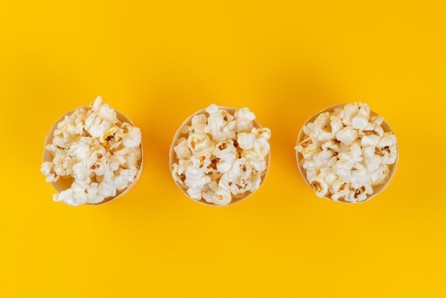 Una vista dall'alto popcorn fresco salato e gustoso su giallo, semi di mais spuntino