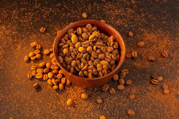 Una vista dall'alto semi di caffè marrone all'interno del piatto marrone sul tavolo marrone