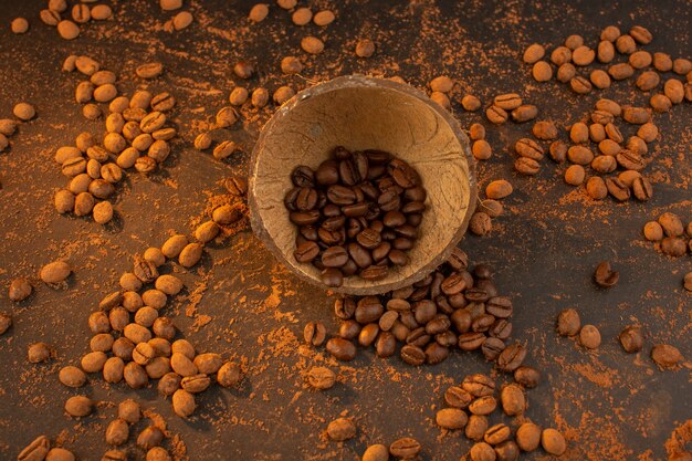 Una vista dall'alto semi di caffè marrone all'interno e all'esterno del guscio di noce di cocco sul tavolo marrone