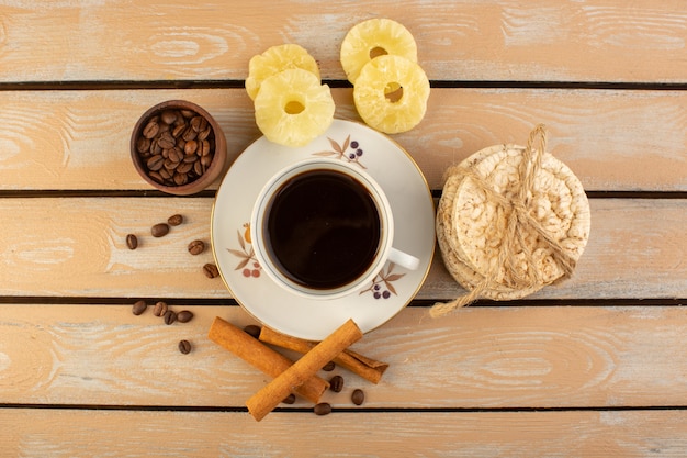 Una vista dall'alto tazza di caffè caldo e forte con semi di caffè marroni freschi cannella e cracker sulla scrivania rustica crema di semi di caffè bevanda foto grano