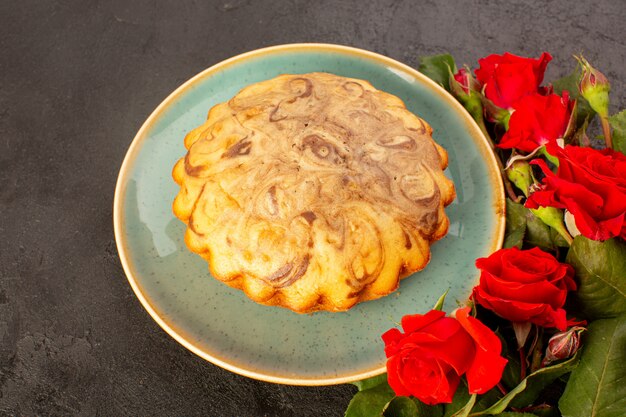 Una vista dall'alto tondo dolce torta deliziosa deliziosa torta al cioccolato all'interno del piatto blu insieme a rose rosse isolate su sfondo grigio zucchero tè biscotto cuocere