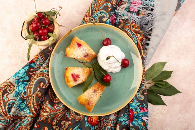 Una vista dall'alto torta di frutta al forno deliziosa affettata con ciliegie rosse all'interno e zucchero in polvere all'interno del piatto verde rotondo