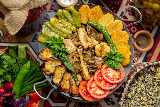 Una vista dall'alto verdure cotte come pomodori rossi verde peperone melanzane nere e patate all'interno del piatto sul piatto