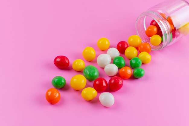 Una vista frontale caramelle colorate dolci e appiccicose sul colore rosa, confetteria a base di zucchero di colore