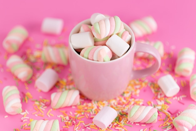 Una vista frontale che mastica marshmallow all'interno di rosa, tazza e tutto in rosa, confettura di zucchero arcobaleno di colore