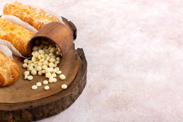 Una vista frontale deliziose torte lunghe con pacchi di carta e noci sulla scrivania rosa