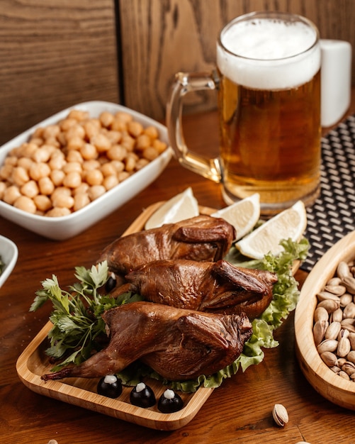 Una vista frontale di carne fritta con noci arachidi e birra sul pasto a base di carne marrone scrivania