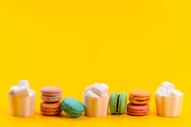 Una vista frontale francese macarons insieme a bianco, marshmallow isolato su giallo, pasticceria dolci torta