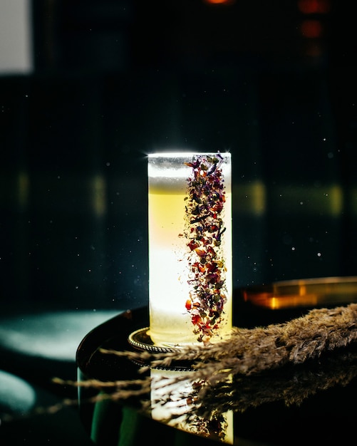 Una vista frontale ghiacciata cocktail fresco e glassa all'interno di un lungo bicchiere sulla superficie scura scura con cocktail bar succhi di frutta
