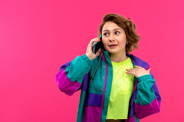 Una vista frontale giovane bella signora in camicia di colore acido pantaloni neri giacca colorata parlando al telefono