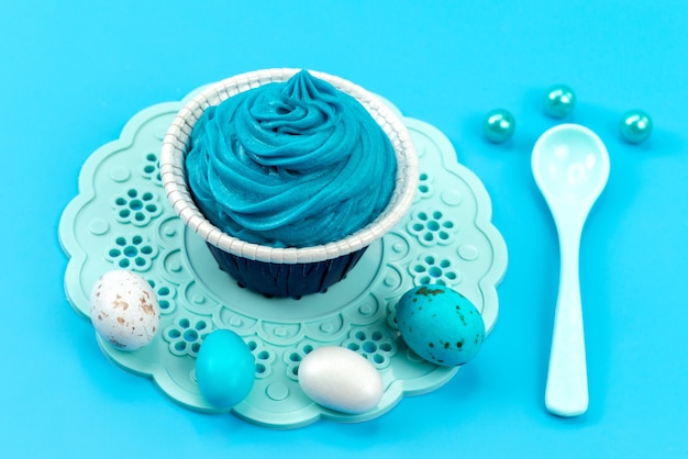 Una vista frontale ha colorato le uova con il bianco, cucchiaio isolato sul colore blu, design