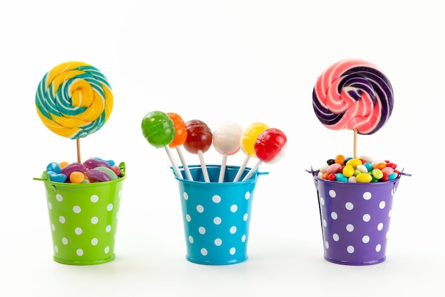 Una vista frontale lecca-lecca e caramelle all'interno di piccoli cestini di colore bianco, confettura di zucchero dolce