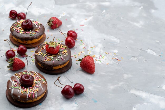 Una vista frontale piccole ciambelle al cioccolato con frutti progettati sulla torta di frutta superiore