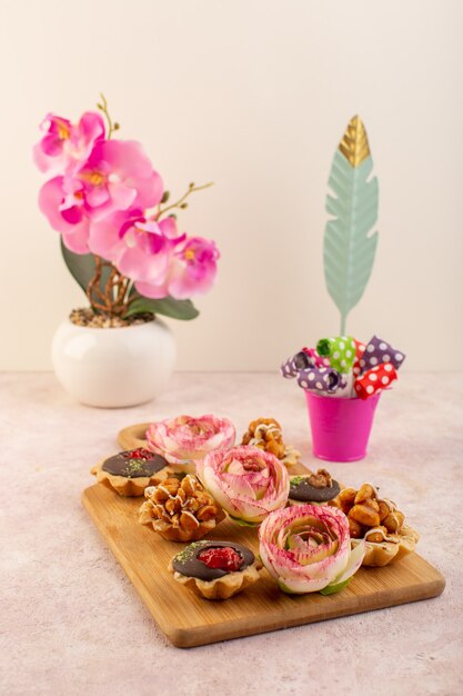 Una vista frontale piccole torte al cioccolato con fiore sulla scrivania rosa