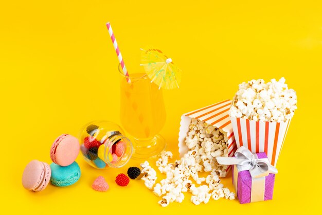 Una vista frontale popcorn e cocktail con macarons francesi e confitures su giallo