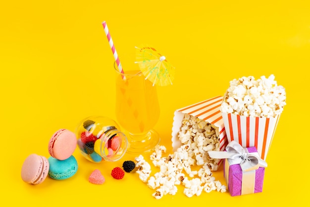 Una vista frontale popcorn e cocktail con macarons francesi e confitures su giallo