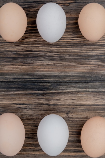 Una vista superiore di tre uova di gallina disposte su uno sfondo di legno con copia spazio