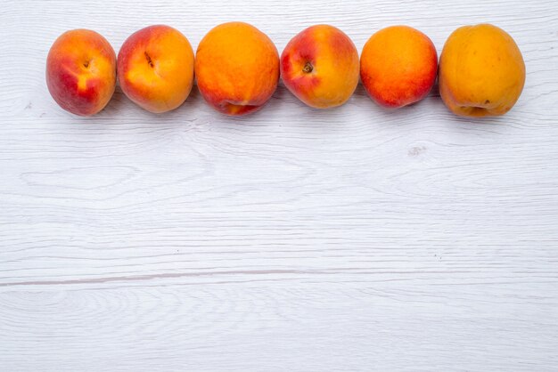 Una vista superiore pesche fresche e pastose sullo sfondo bianco frutta di colore fresco