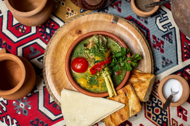 Una zuppa calda vista dall'alto con verdure e carne insieme a pezzi di pane sulla scrivania rotonda in legno marrone