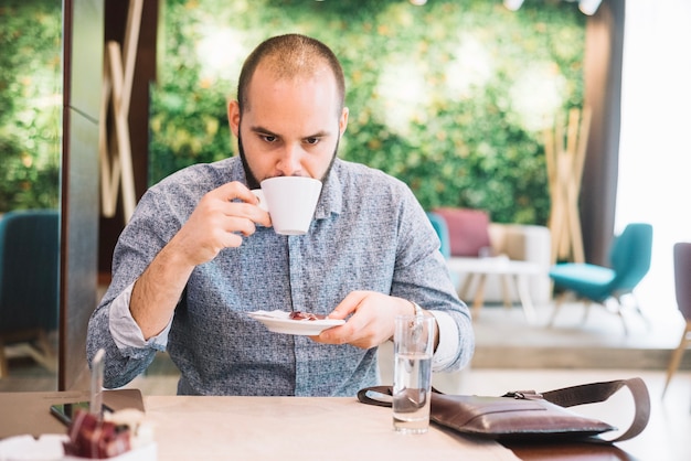 Unemotional uomo bere caffè in caffetteria