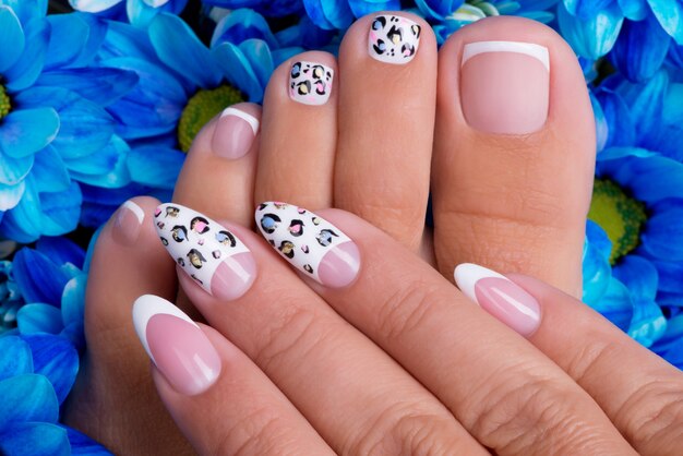 Unghie delle mani e delle gambe della bella donna con bella french manicure e art design