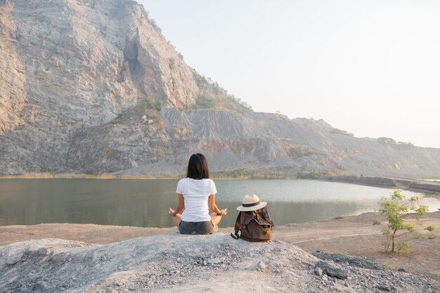 Unità con la natura. giovane donna che fa meditare all'aperto vicino al lago