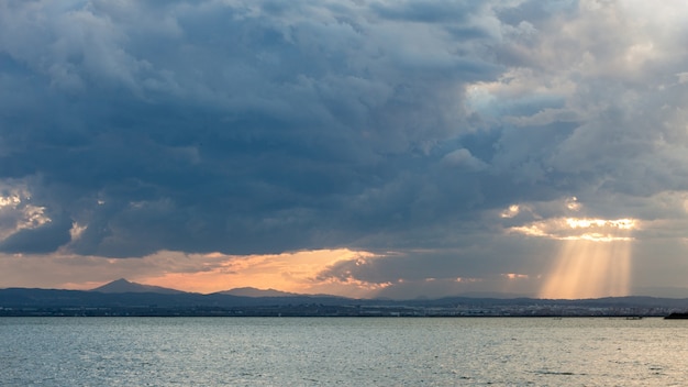Uno scenario mozzafiato del tramonto che splende attraverso le nuvole sul mare tranquillo