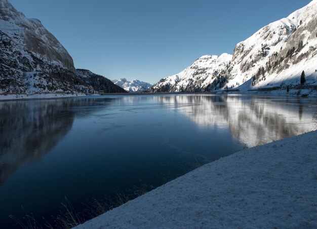 Uno splendido scenario di alte montagne innevate che si riflettono sul lago nelle Dolomiti