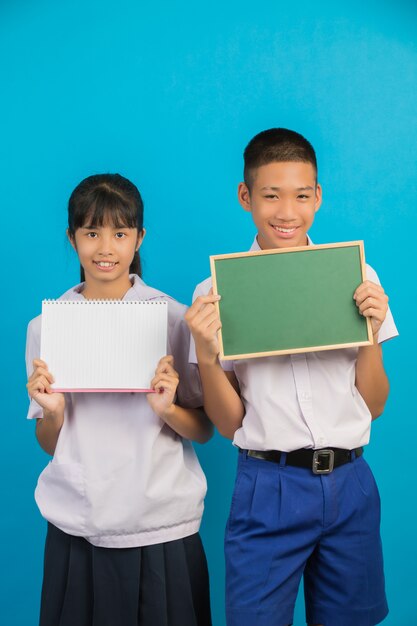 Uno studente asiatico in possesso di un taccuino e studente maschio asiatico in possesso di un bordo verde su un blu.
