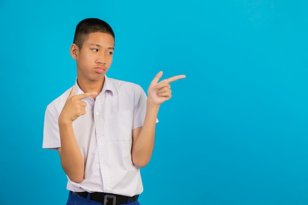 Uno studente maschio asiatico maschio con una mano ha sollevato il suo gesto che indica contro l'azzurro.