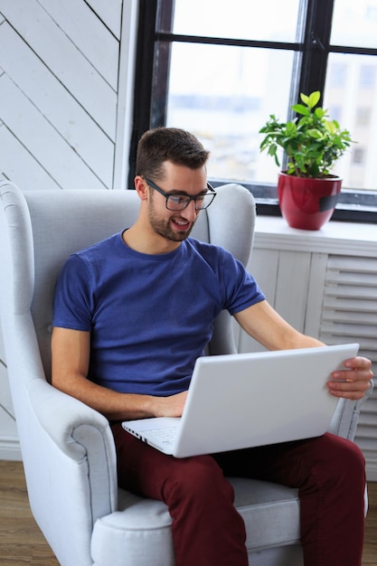 Uno studente seduto sulla sedia e che lavora con il laptop.