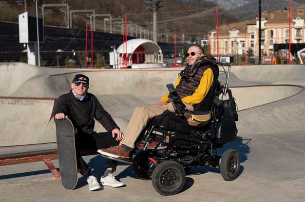 Uomini a figura intera con sedia a rotelle e skateboard