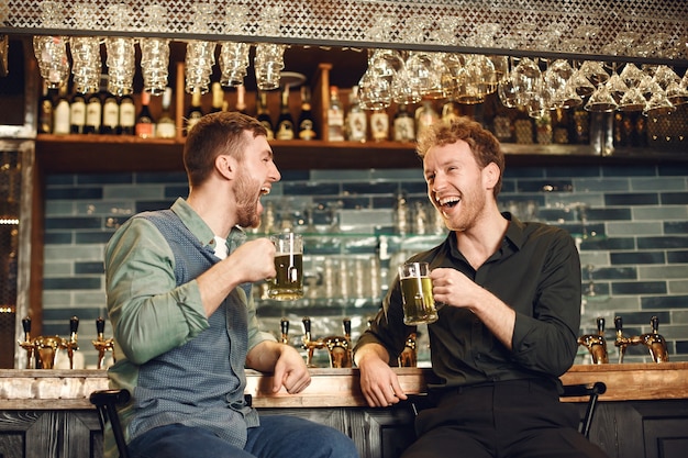 Uomini al bar. Ragazzi che bevono birra. Gli uomini comunicano davanti a un boccale di birra.