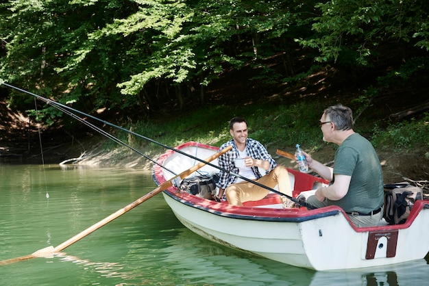 Uomini allegri che pescano in riva al lago