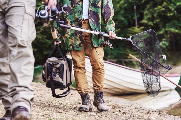 Uomini che camminano e portano attrezzatura da pesca