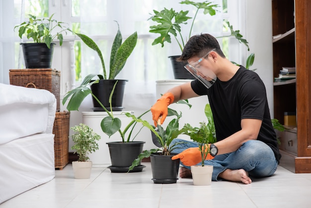 Uomini che indossano guanti arancioni e piantano alberi al chiuso.