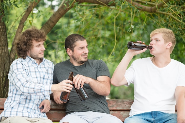 Uomini con birra rilassante sulla panchina